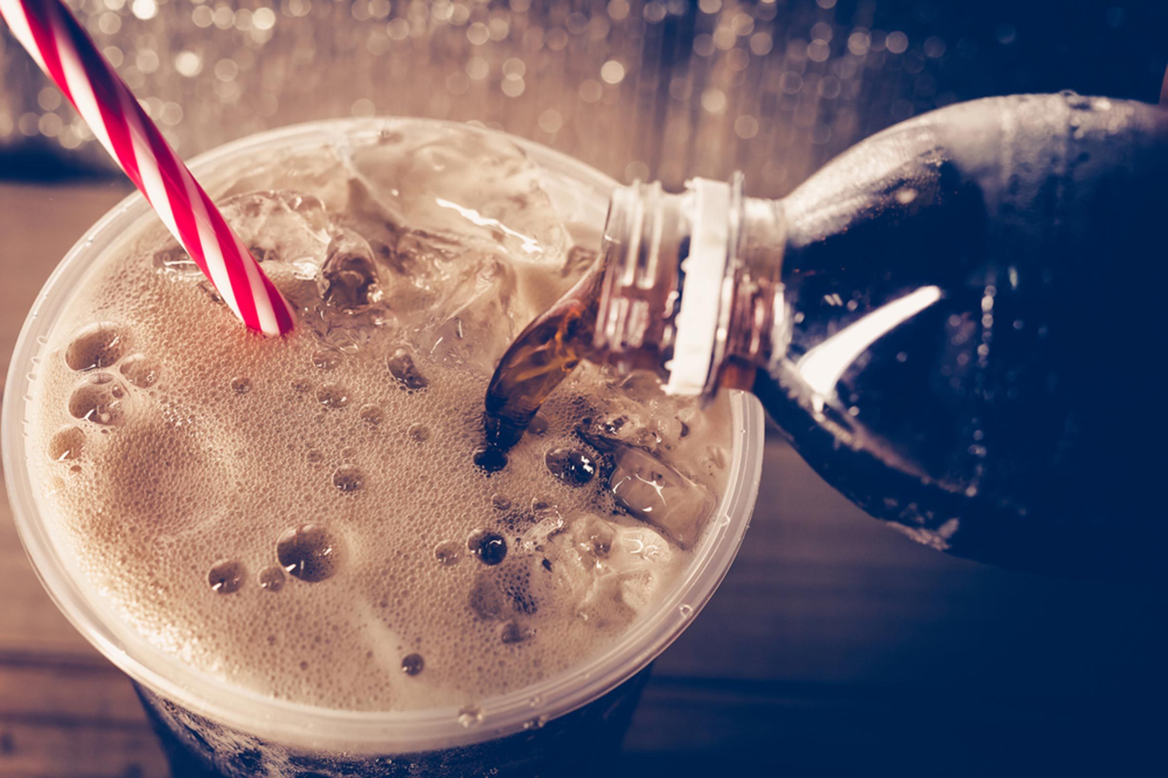 soda being poured into a cup with a straw