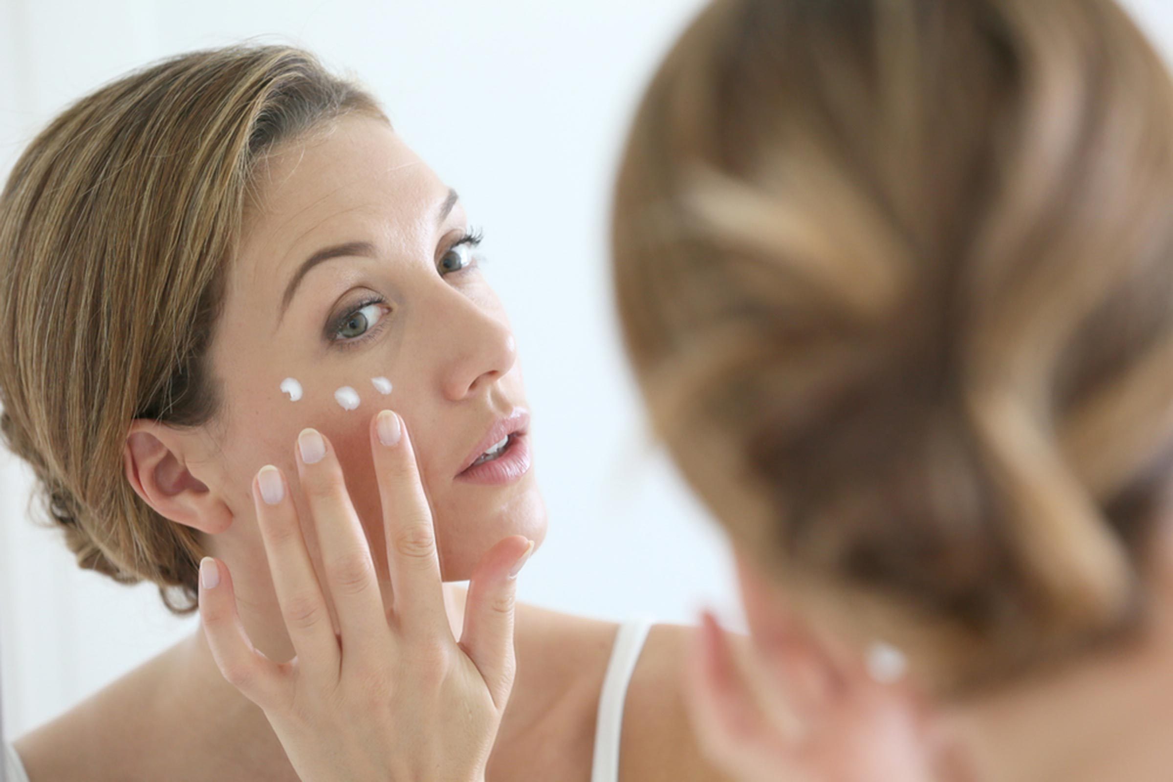 Woman dabbing retinol under her eye.