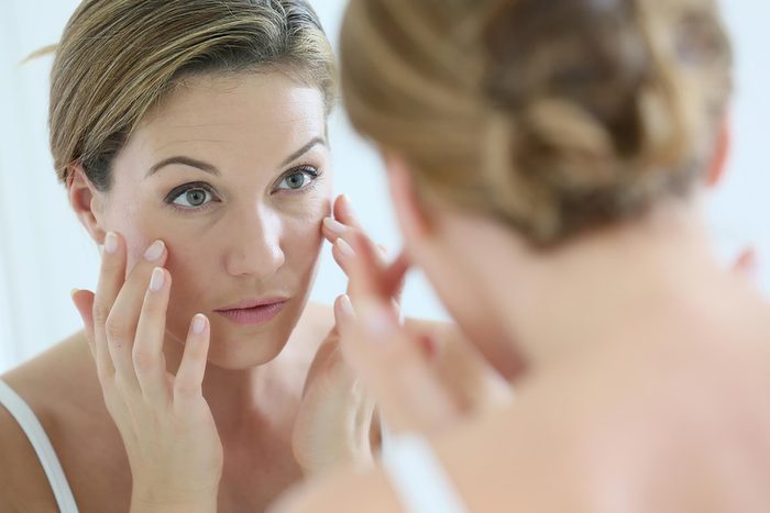 Woman looking at face in the mirror