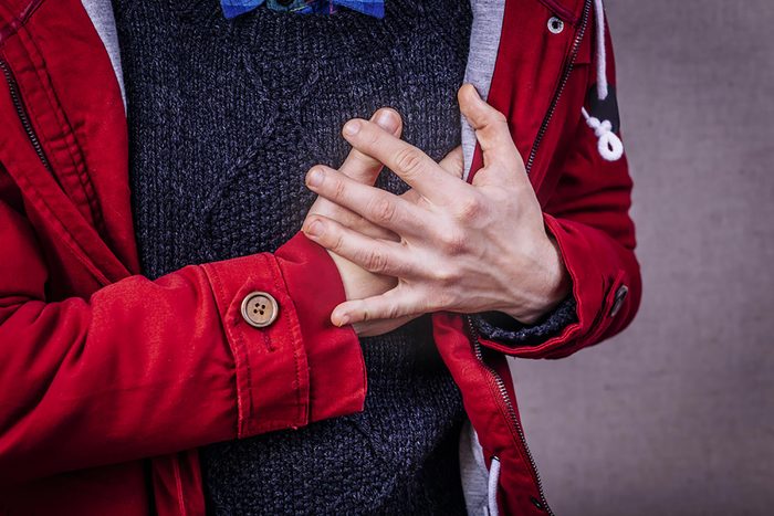 man in a sweater and jacket clutching his chest