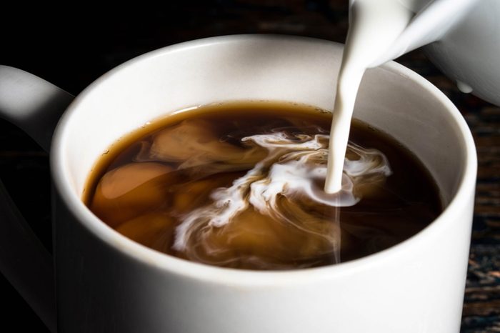 creamer pouring into a coffee mug