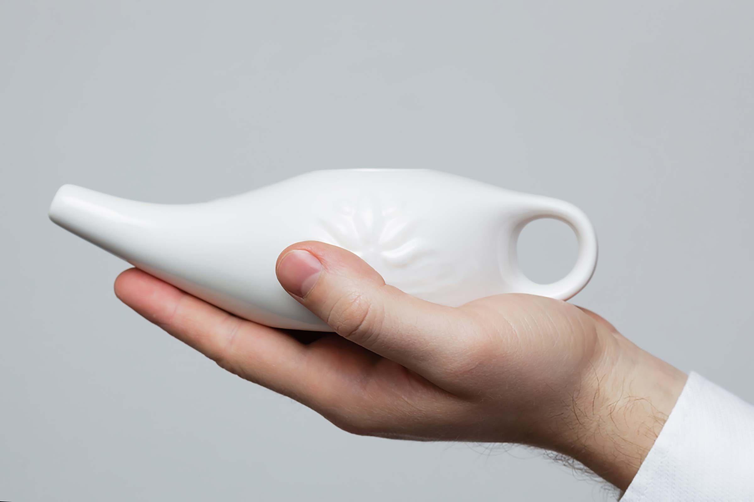 Person holding a white neti-pot
