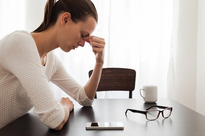 Stressed woman pinching the bridge of her nose with her fingers.