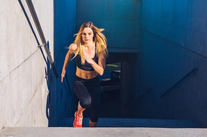 Woman in exercise gear jogging up stairs.
