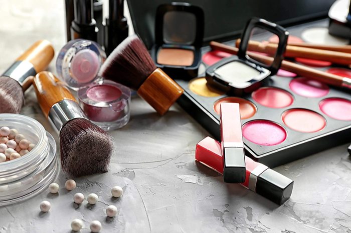 A makeup set, including blushes, lip glosses, and brushes, on a marble counter.