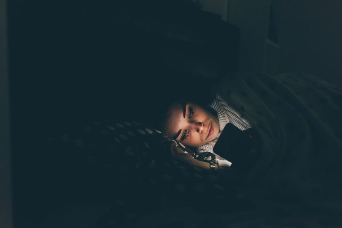 person in bed reading their smartphone