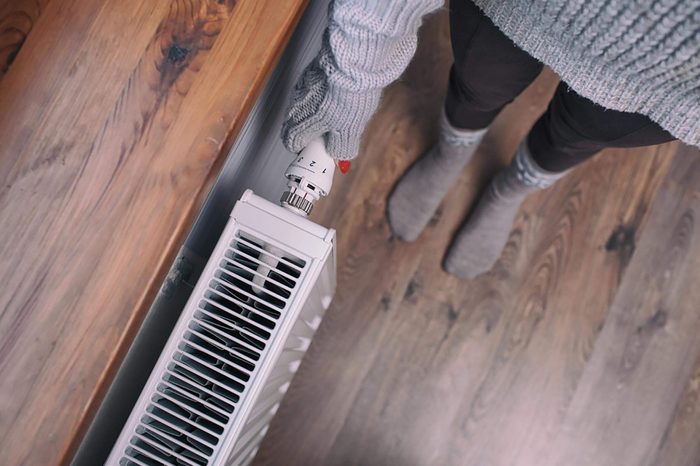 woman with gloves on adjusting a heater