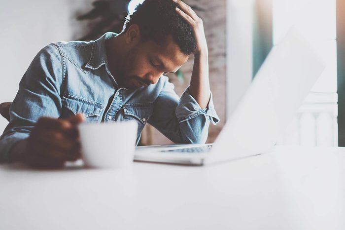 man sitting at a computer resting his head in his hand