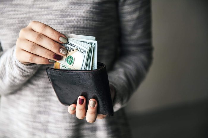 woman putting $100s into her billfold