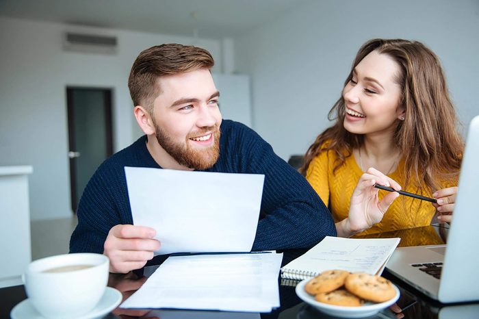 a couple discussing paperwork next to a laptop