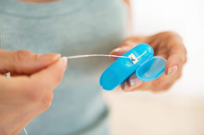 woman pulling floss out of a blue floss container