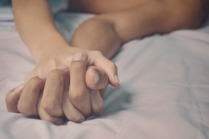 A man and woman holding hands together in bed.