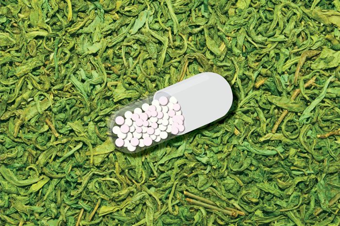 Illustration of an L-theanine capsule against a background of green tea leaves.