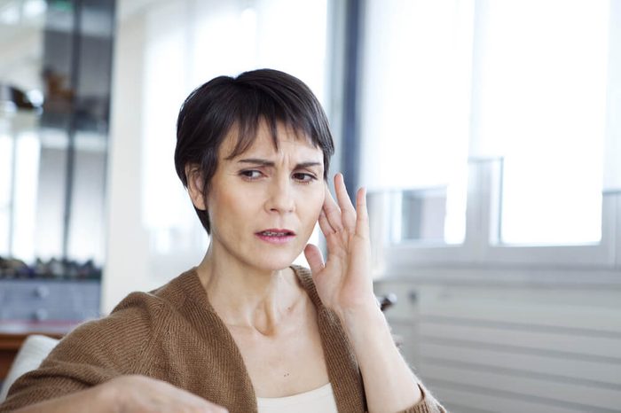 woman with a worried expression holding her hand to her ear
