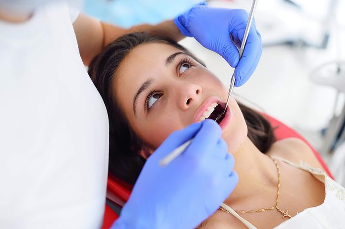 woman in dental chair with mouth open, Dentist holding tools