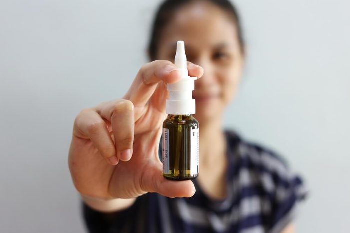 Female holding a nasal spray bottle.