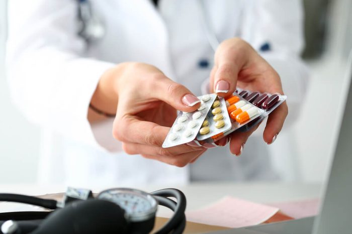 Hands of a female doctor holding packs of pills and capsules in blister packaging.