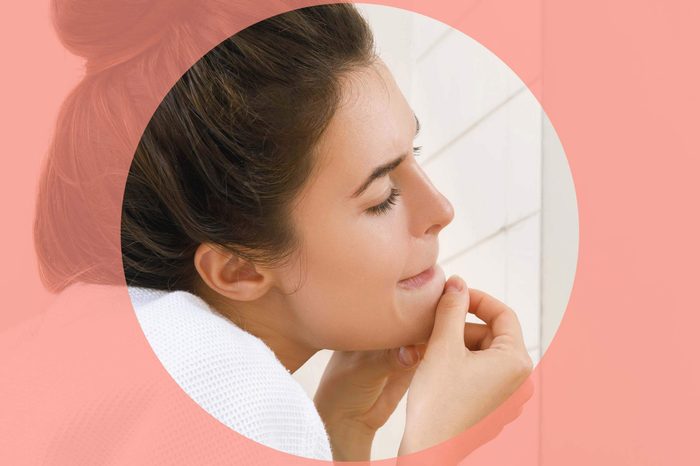 woman looking in the mirror and squeezing a pimple