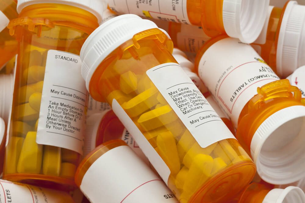 Bottles of prescription medicine in a pile. This collection of pill containers is symbolic of the many medications senior adults and chronically ill people take. 