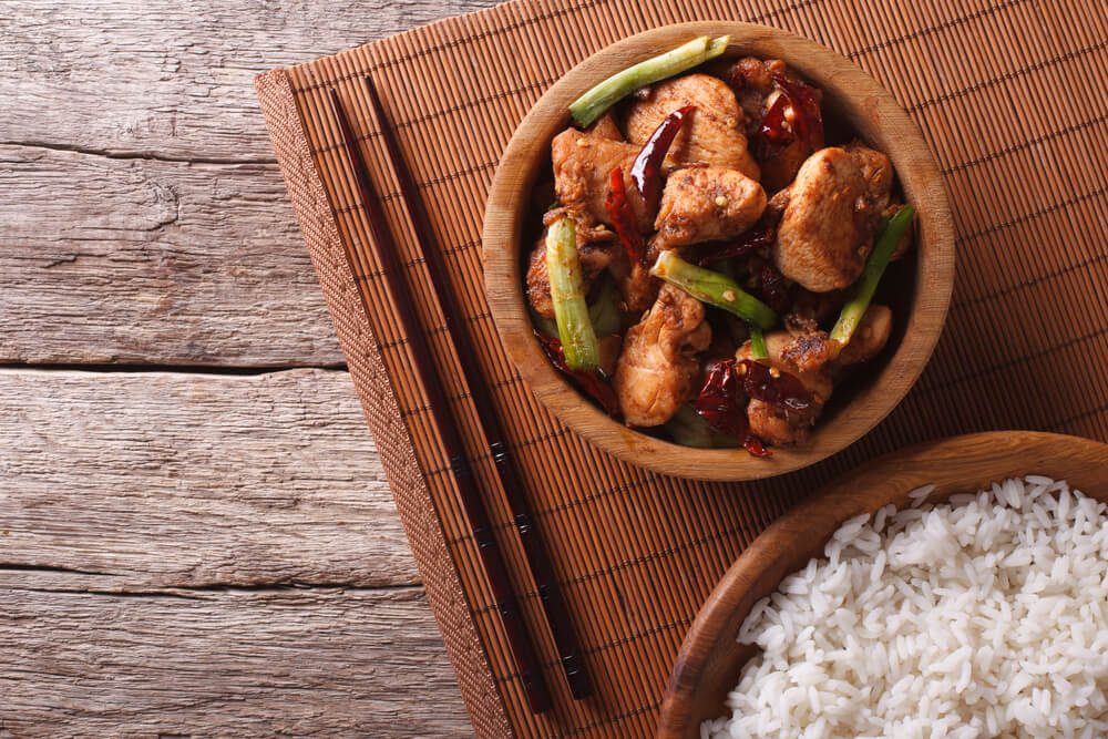 Kung pao chicken fillets in a bowl and rice. horizontal view from above