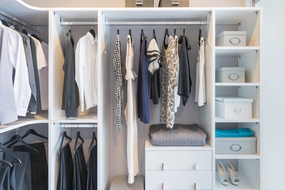 clothes hanging on rail in white wardrobe with box and shoes