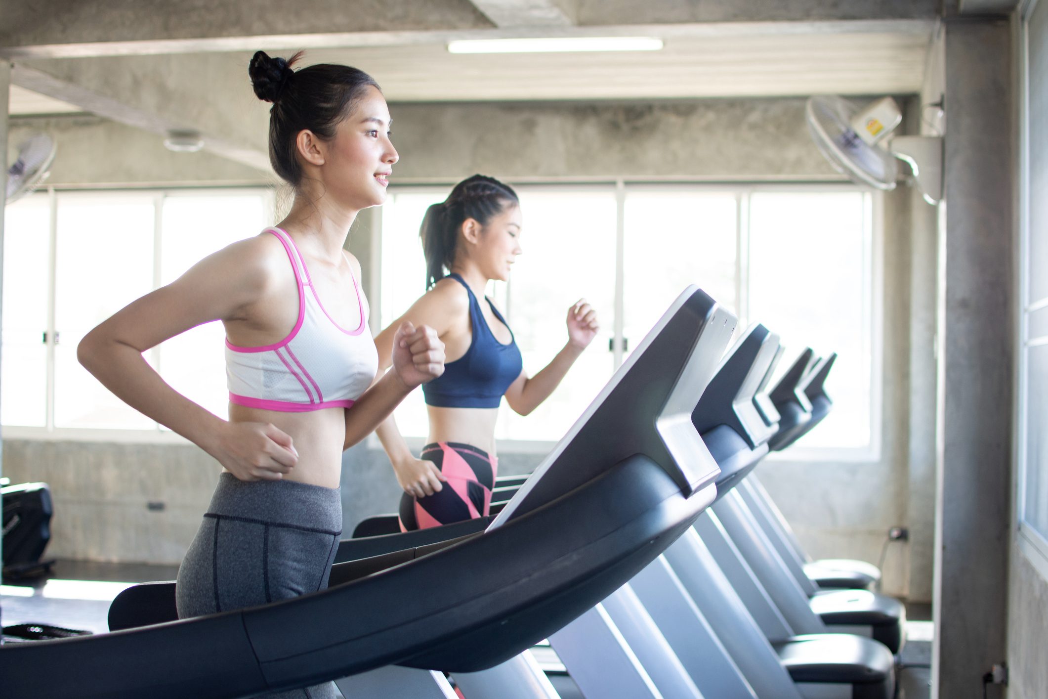 two young women running on treadmils