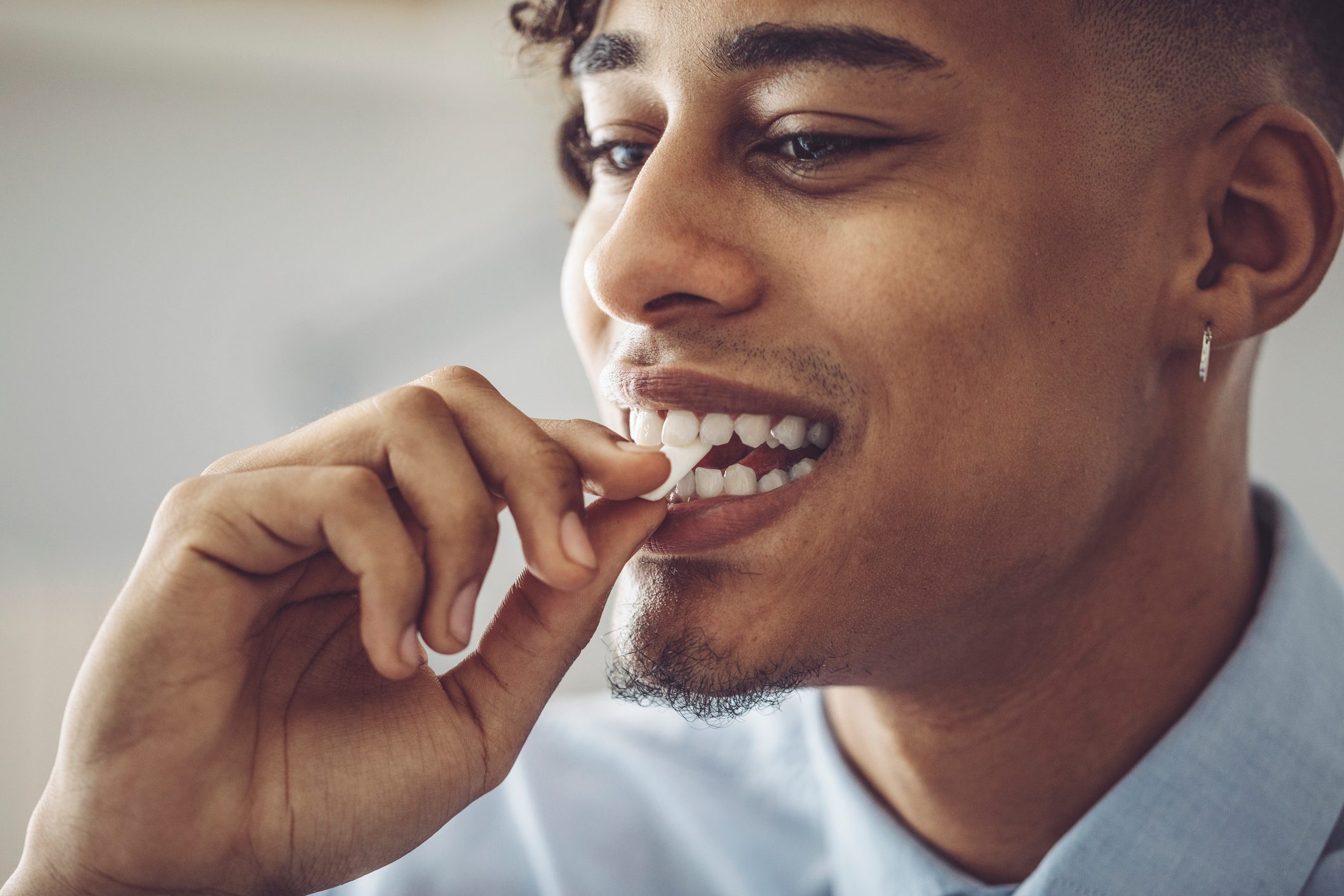 man putting chewing gum into his mouth