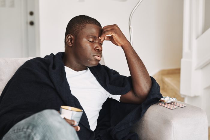 man sitting on couch sick with headache