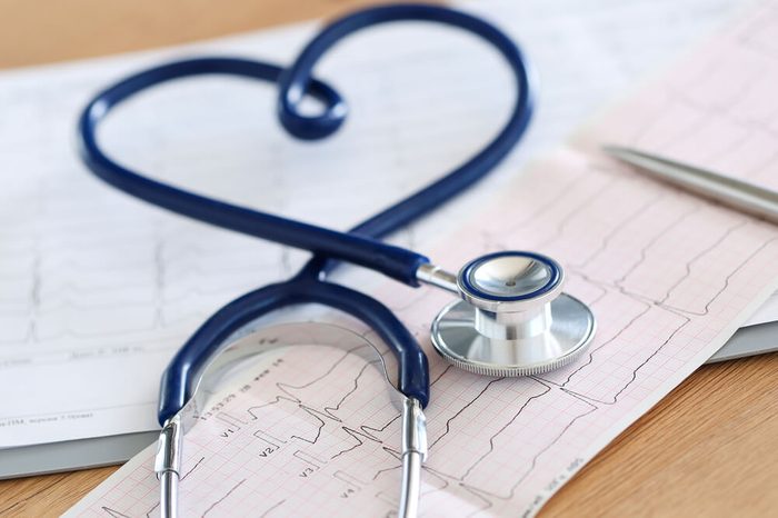 stethoscope twisted in heart shape lying on cardiogram chart closeup