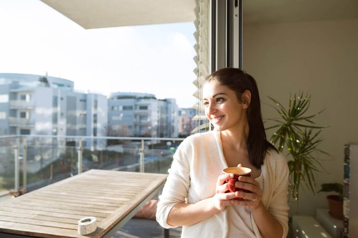 smiling woman on balcony holding mug