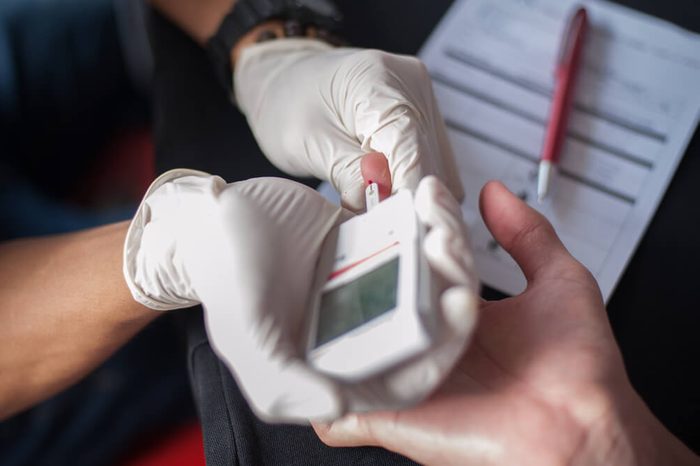doctor or nurse inserting glucose test strip into glucometer