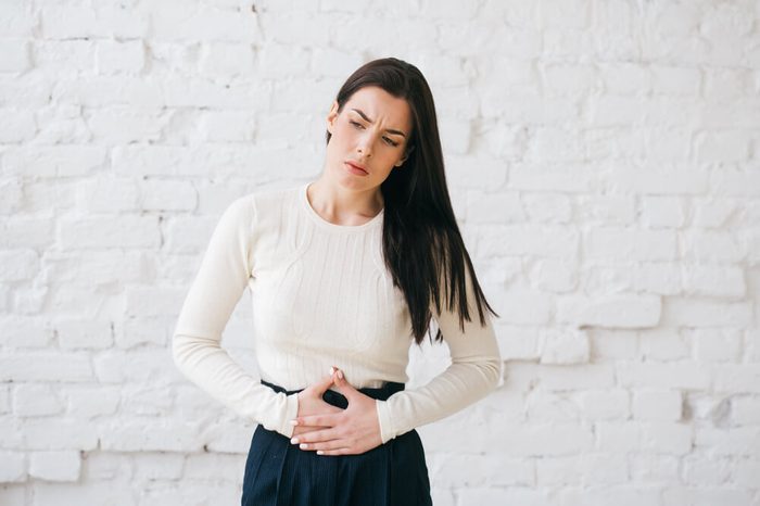 Grimacing woman with hands over stomach