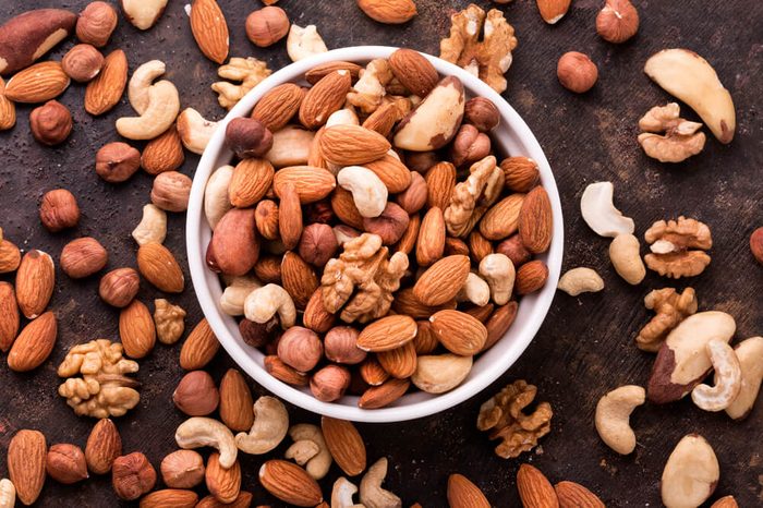 Mixed Nuts in a white bowl and spilled around on a table