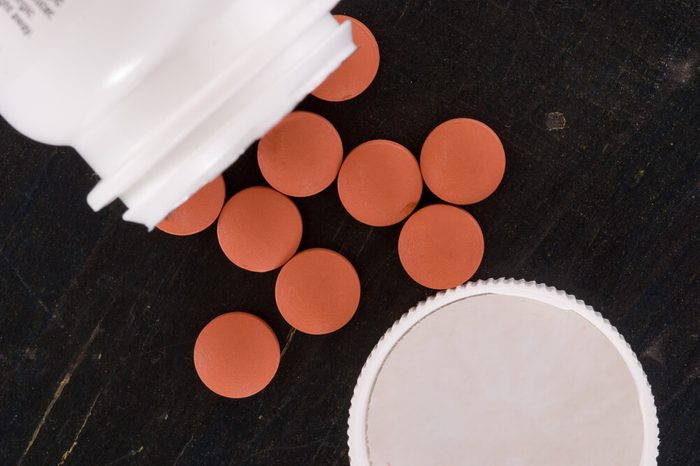 Over the counter medication on black table with bottle and cap