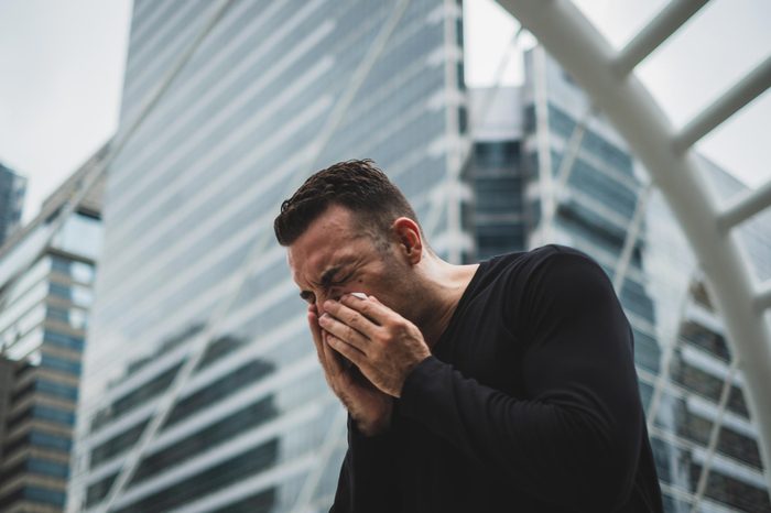 man sneezing city allergies cold sick