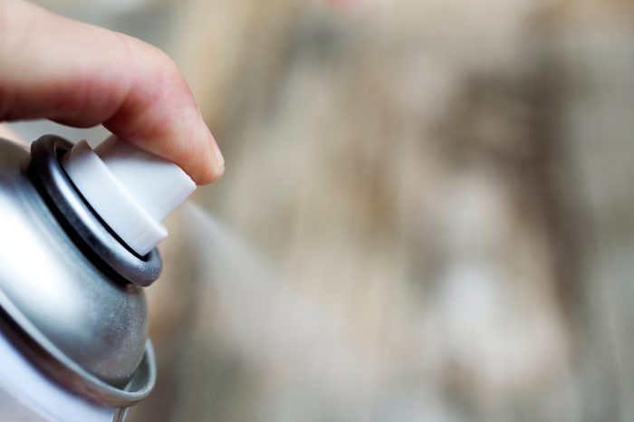 closeup of a hand spraying the product of an aerosol can