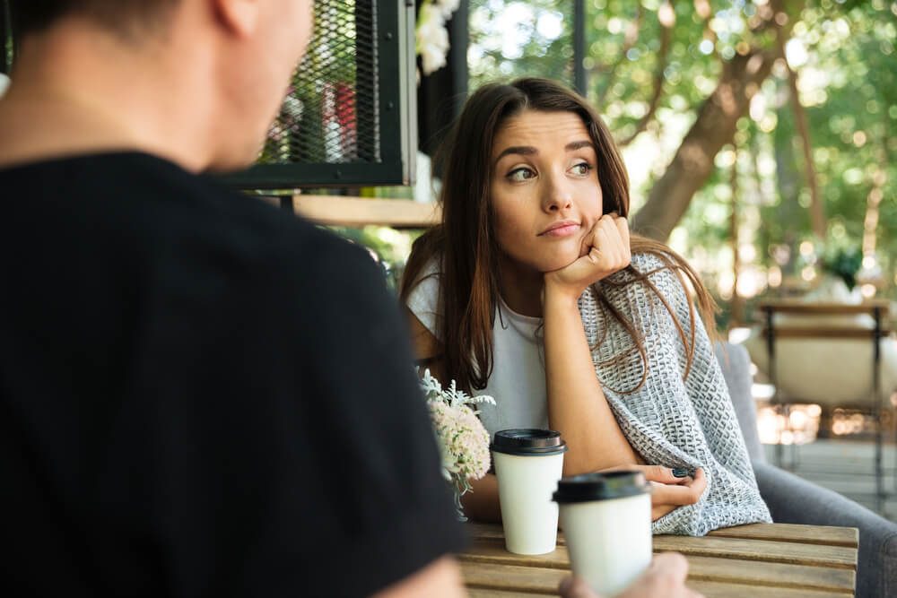 Bored girl drinking coffee with her boyfriend and looking away