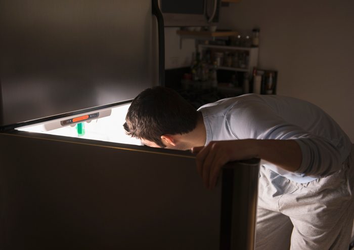 man opening refrigerator at night