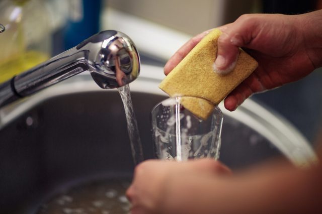 close up washing dishes. male hands in foam washes the frying pan with a detergent and sponge in the kitchen of the house