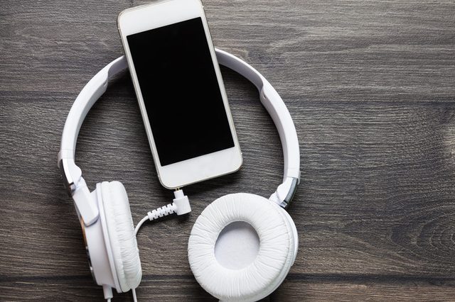 White headphones and smart phone on wooden table