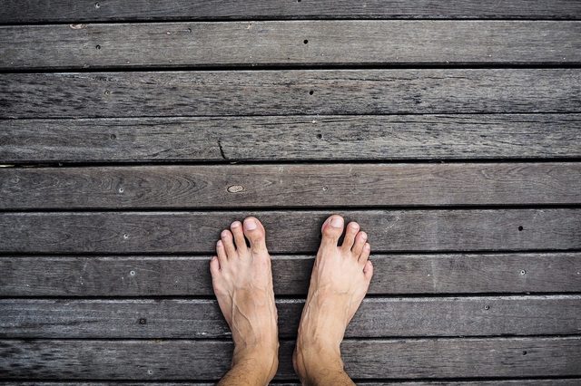 Bare foot standing on wooden floor