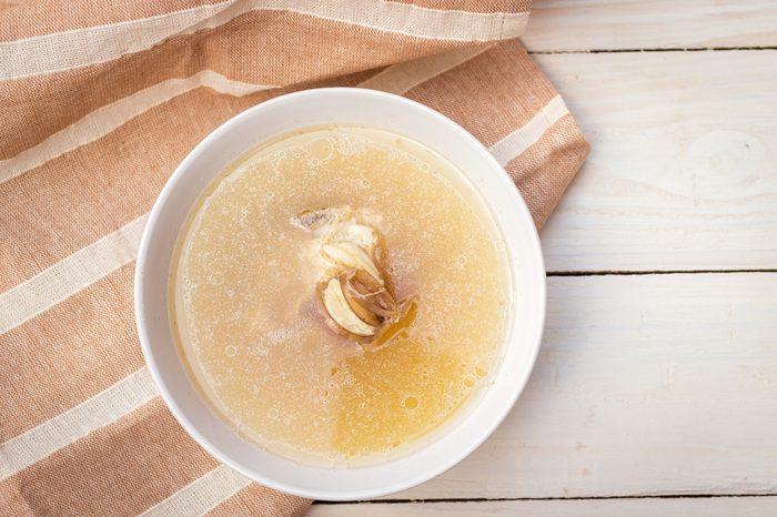 Bowl of pork bone soup with herbs on wood table