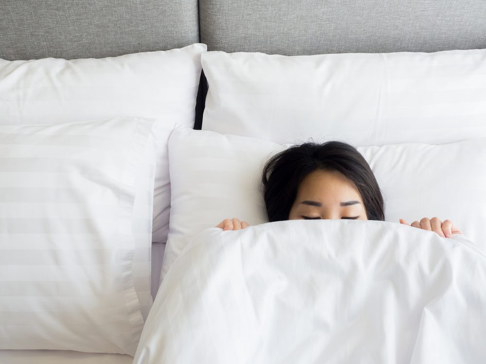 Sleeping woman covering face with blanket