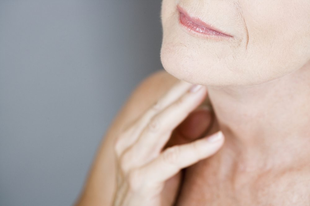 A senior woman touching her neck