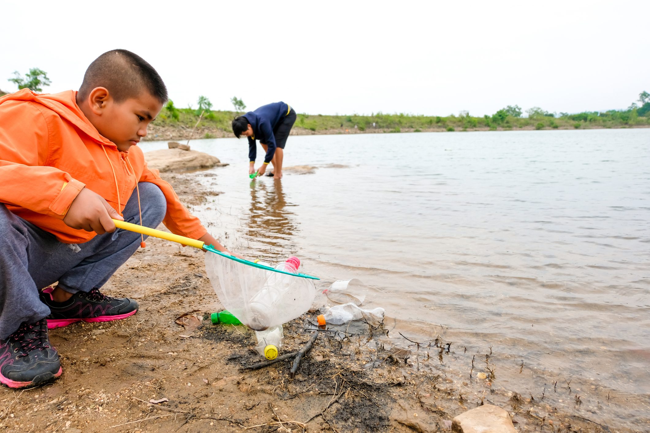 young boy removing trash from river