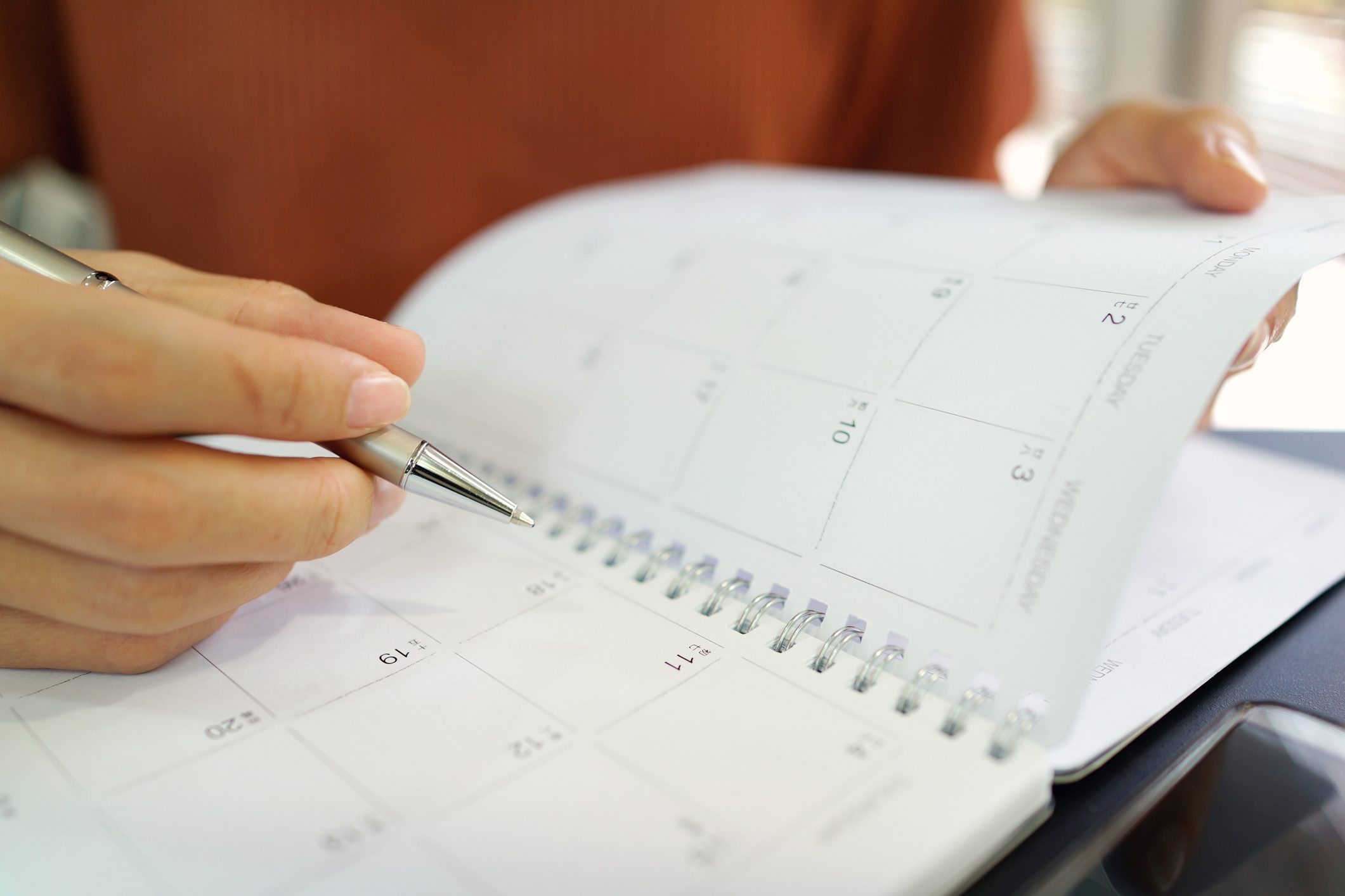 close up of woman holding pen to personal calendar