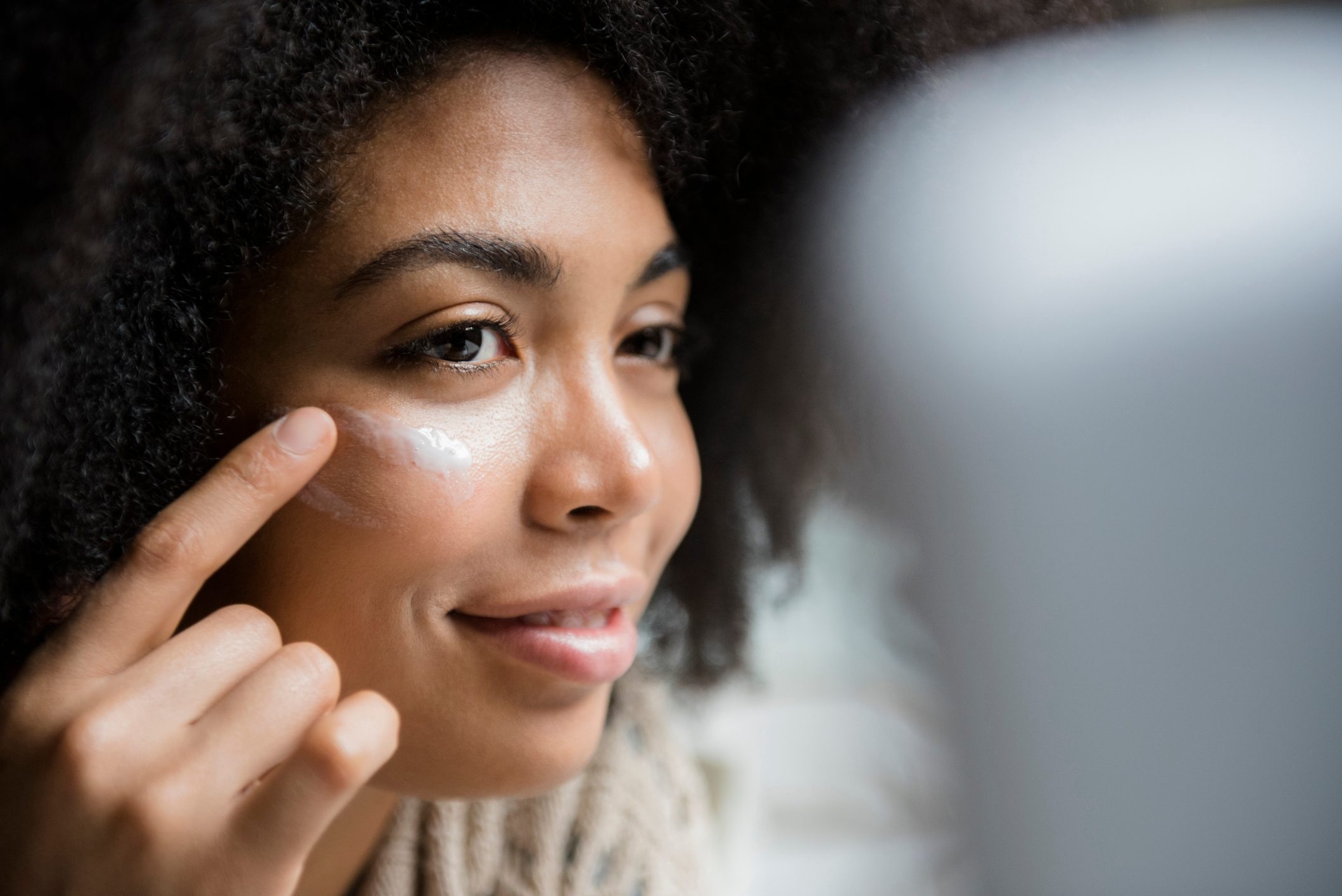 woman applying moisturizer to face