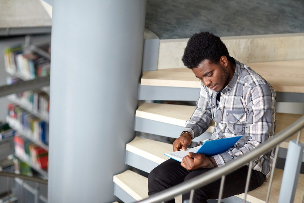 male college student reading on steps