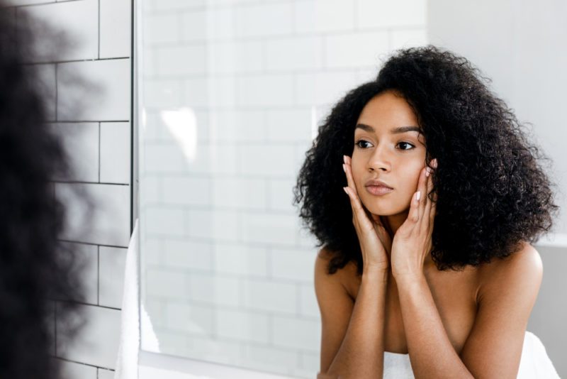 woman looking at face in the mirror
