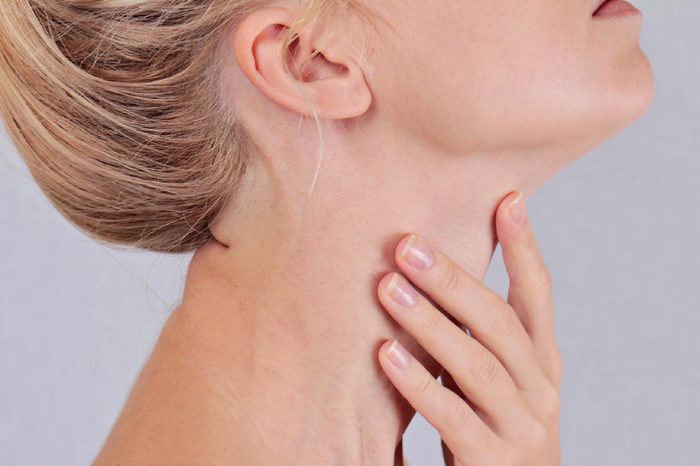 closeup of a woman's neck, head tilted back and hand on throat